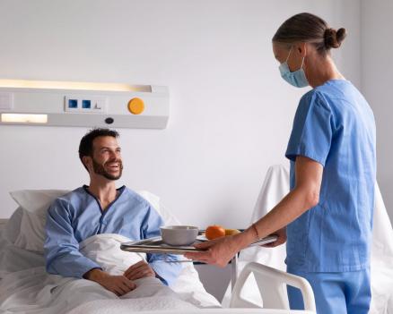 Пациент в больнице получает питание от медперсонала в условиях стационара после операции.