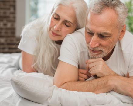 Пожилая пара в постели проявляет заботу и поддержку друг к другу.